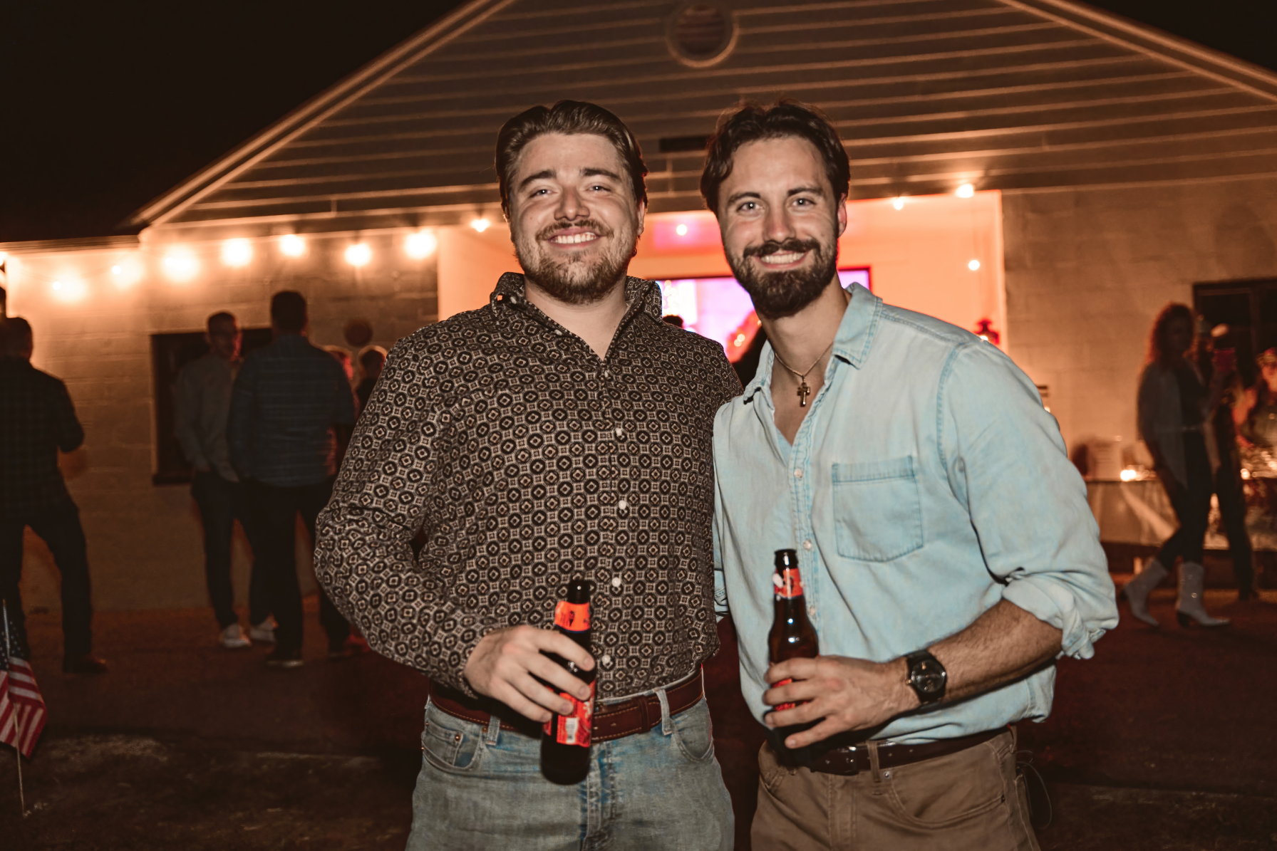 Two guests smiling in front of the string-lit barn