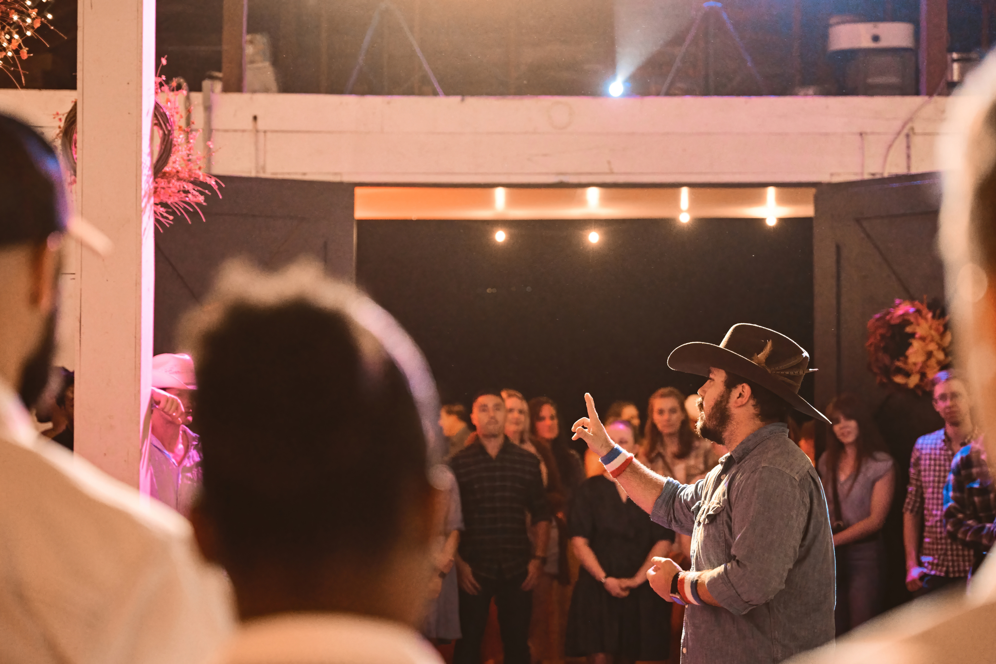 Crowd dancing in the barn under glowing string lights