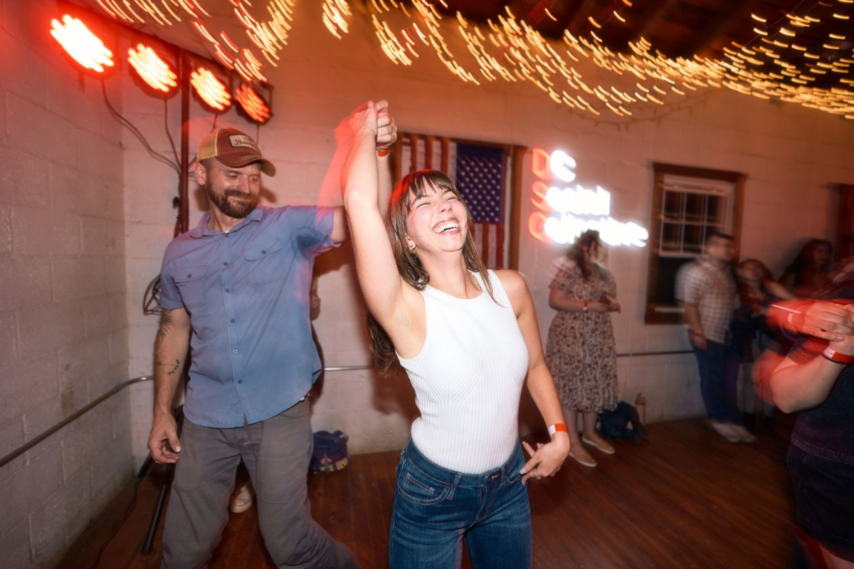 Couple laughing and dancing under red lights with a flag behind them