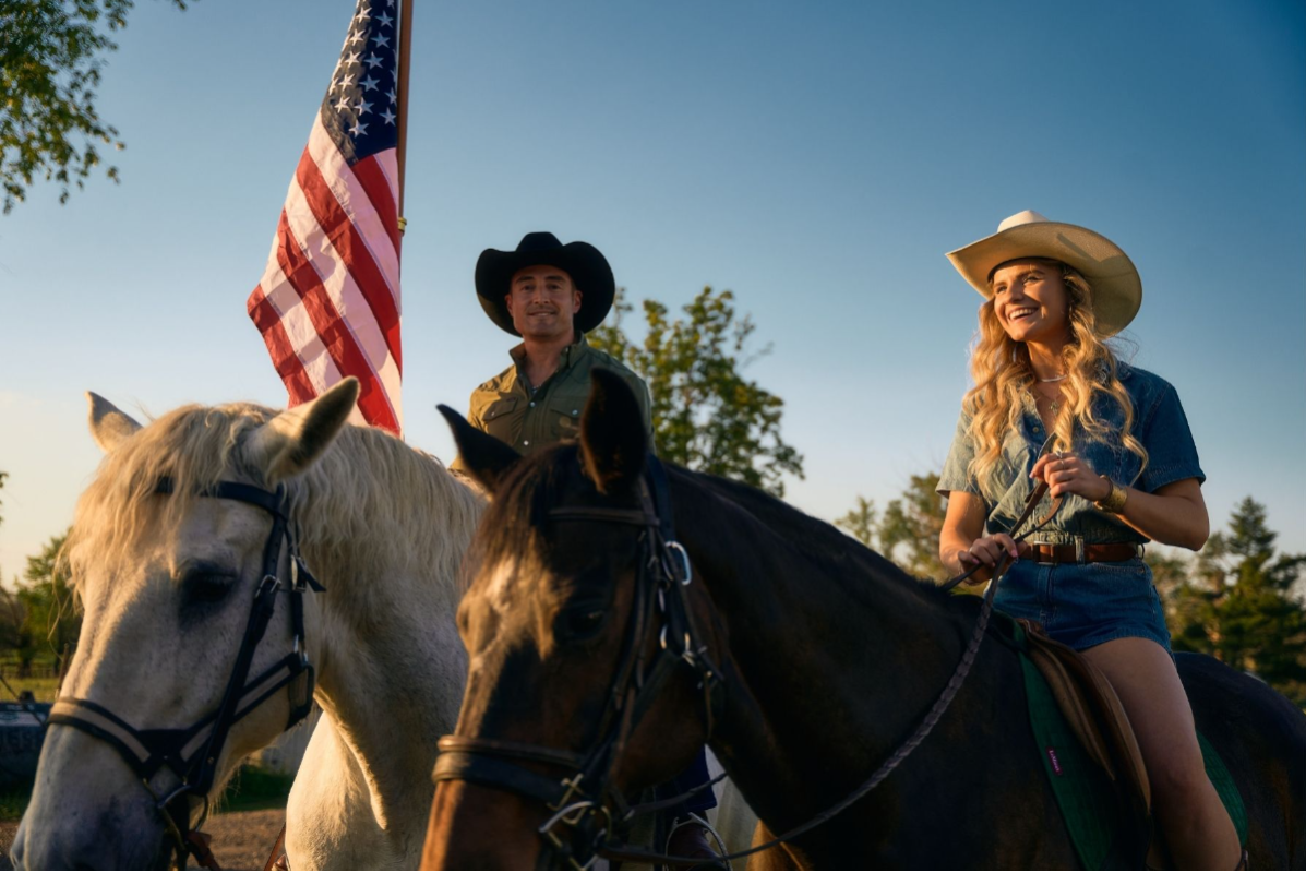 Horseback riding across the field carrying American flags