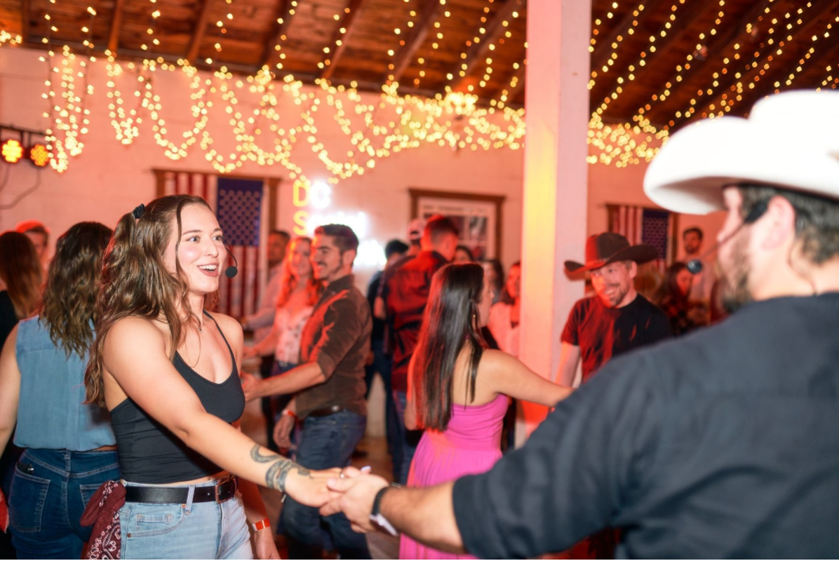 Instructors demonstrating country swing under string lights